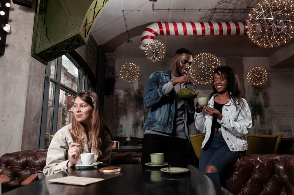 Happy friends enjoying their cups of tea in a shop with holiday decor